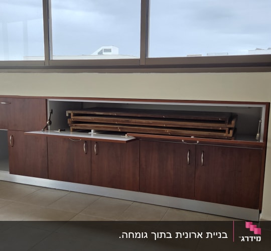ארון עץ עם דלת פתוחה ליד חלון גדול